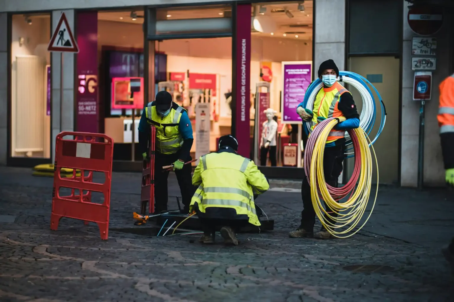 Technicians installing network cabling in a pit in the street